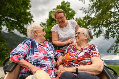 Zwei Seniorinnen sitzen auf der Vorderbank der Rikscha. Sie wenden sich nach hinten und unterhalten sich angeregt mit der Fahrerin der Rikscha.