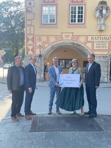 Frau Bürgermeisterin Elisabeth Koch hält ein Schild mit der Aufschrift "Uni-Standort Garmisch-Partenkirchen". Neben ihr stehen Manfred Bachhuber, Alexander Dobrindt, Bernd Sibler und Harald Kühn.